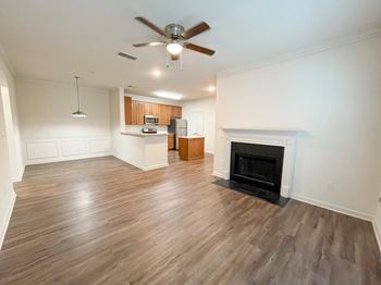 an empty living room with a fireplace and a kitchen at The Crest at Sugarloaf, Lawrenceville, Georgia